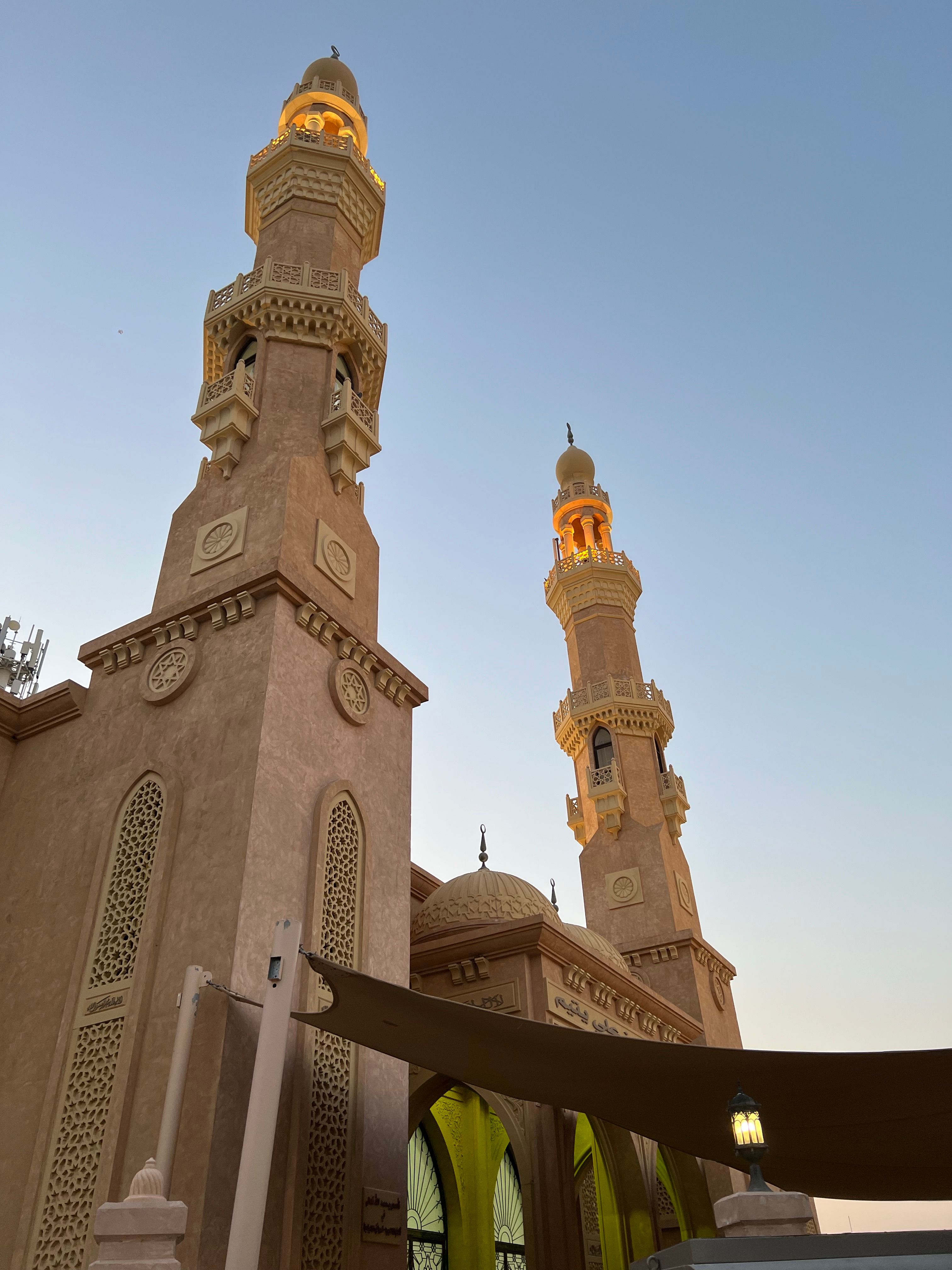 Striking minarets of a mosque tower against a serene sunset sky.