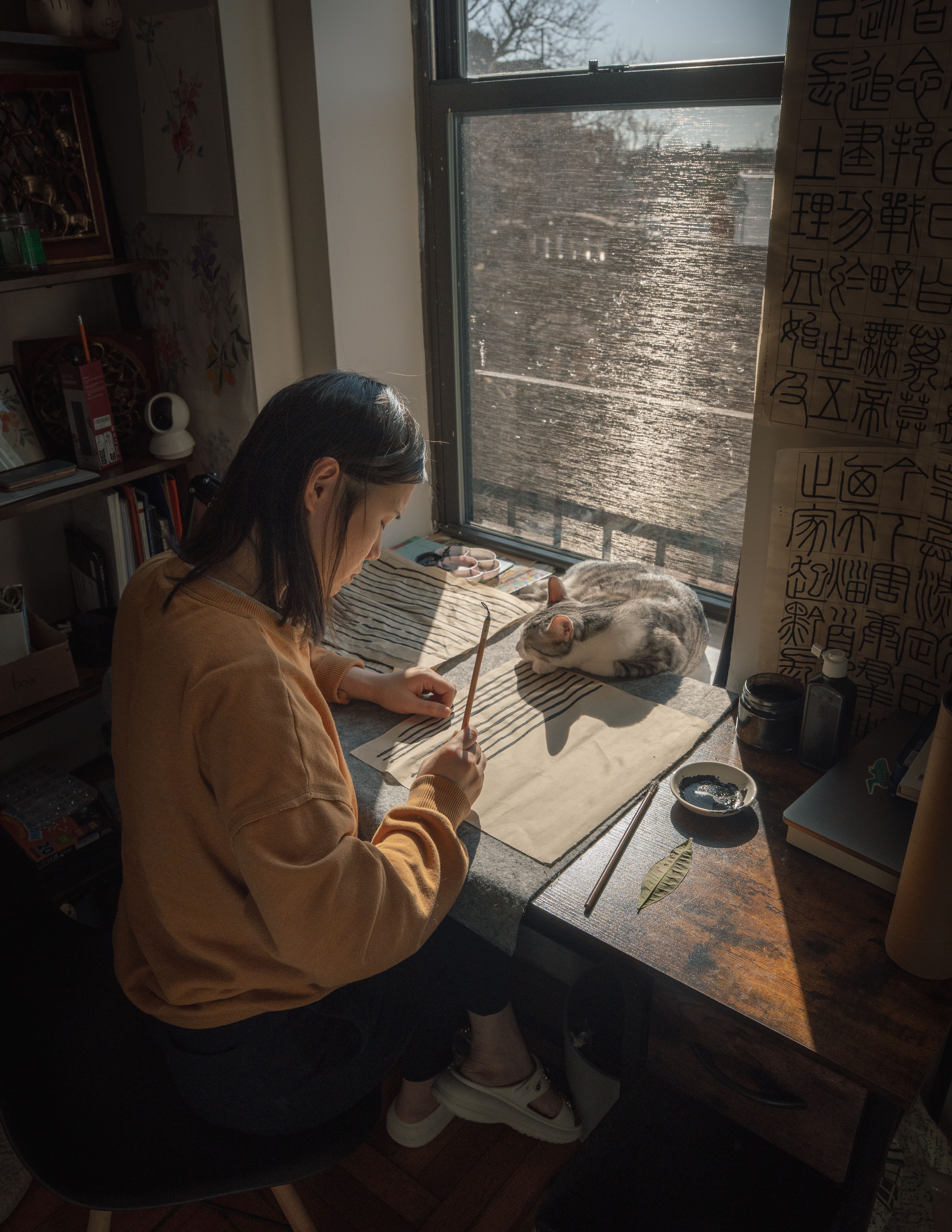 Asian woman practicing calligraphy with cat by window · Free Stock Photo