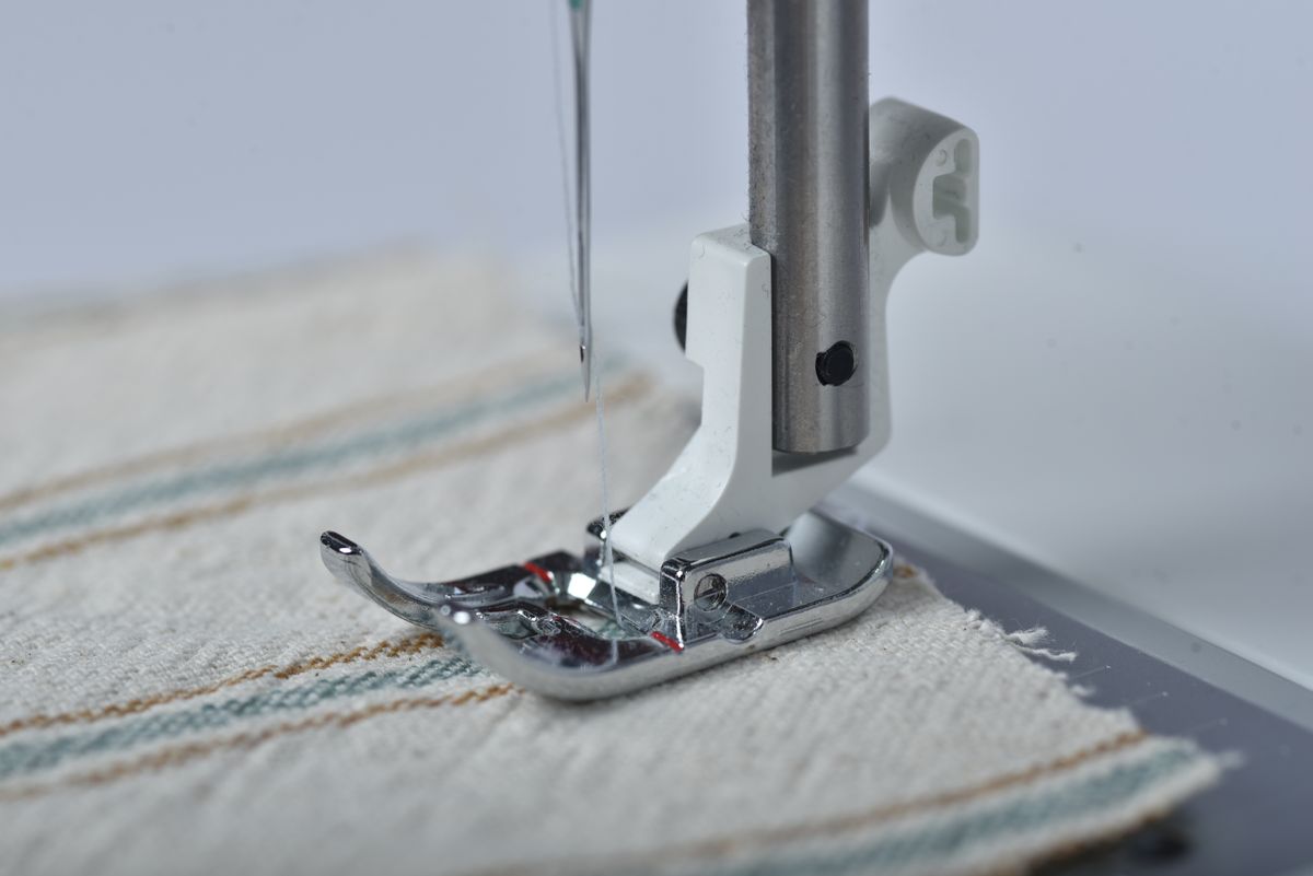 A sewing machine needle stitching through pale fabric