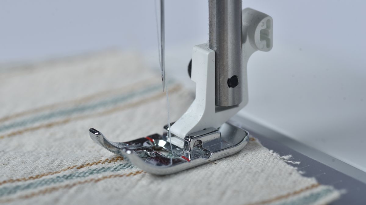 A sewing machine stitching a seam on striped fabric