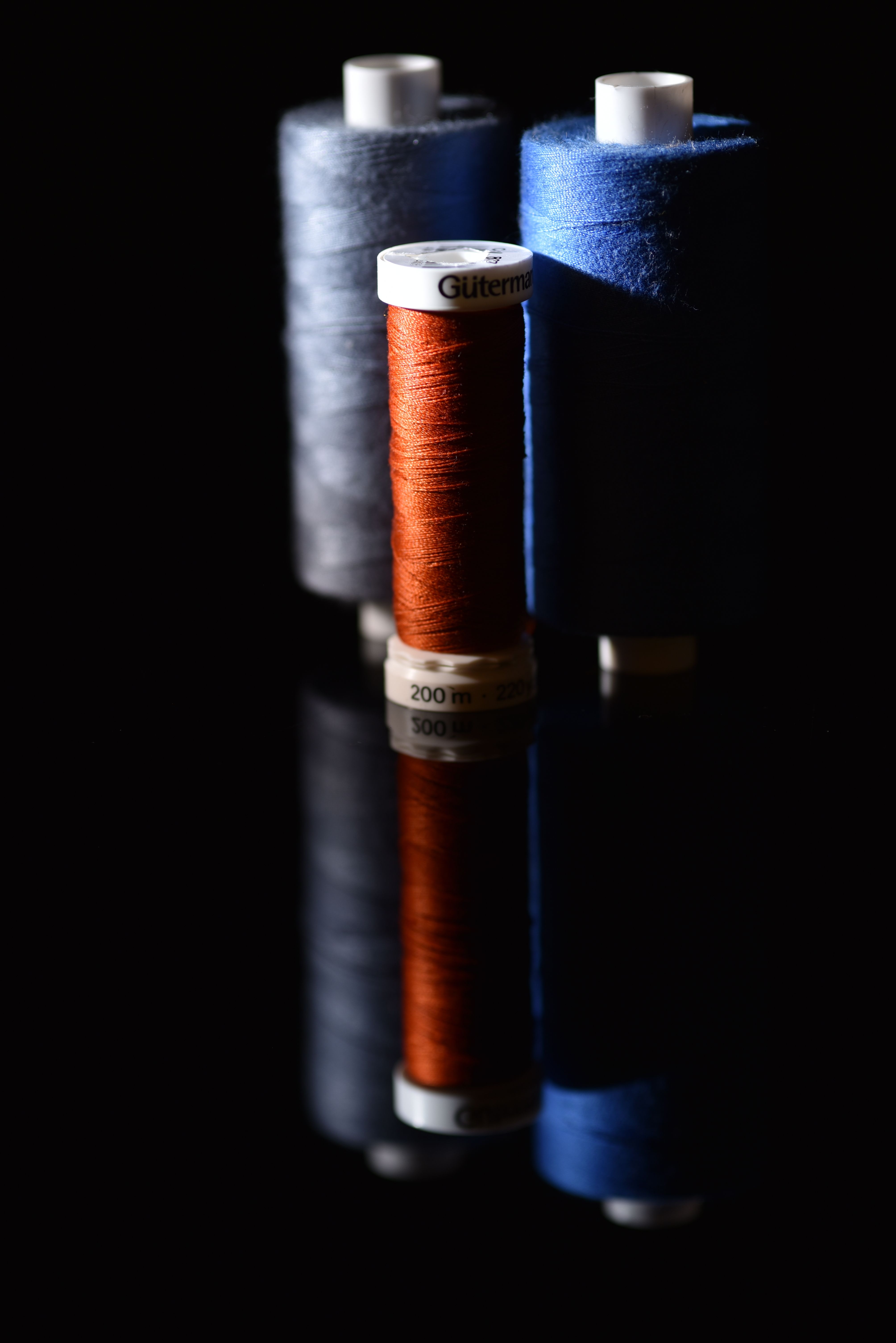 Colorful spools of thread on glossy surface · Free Stock Photo