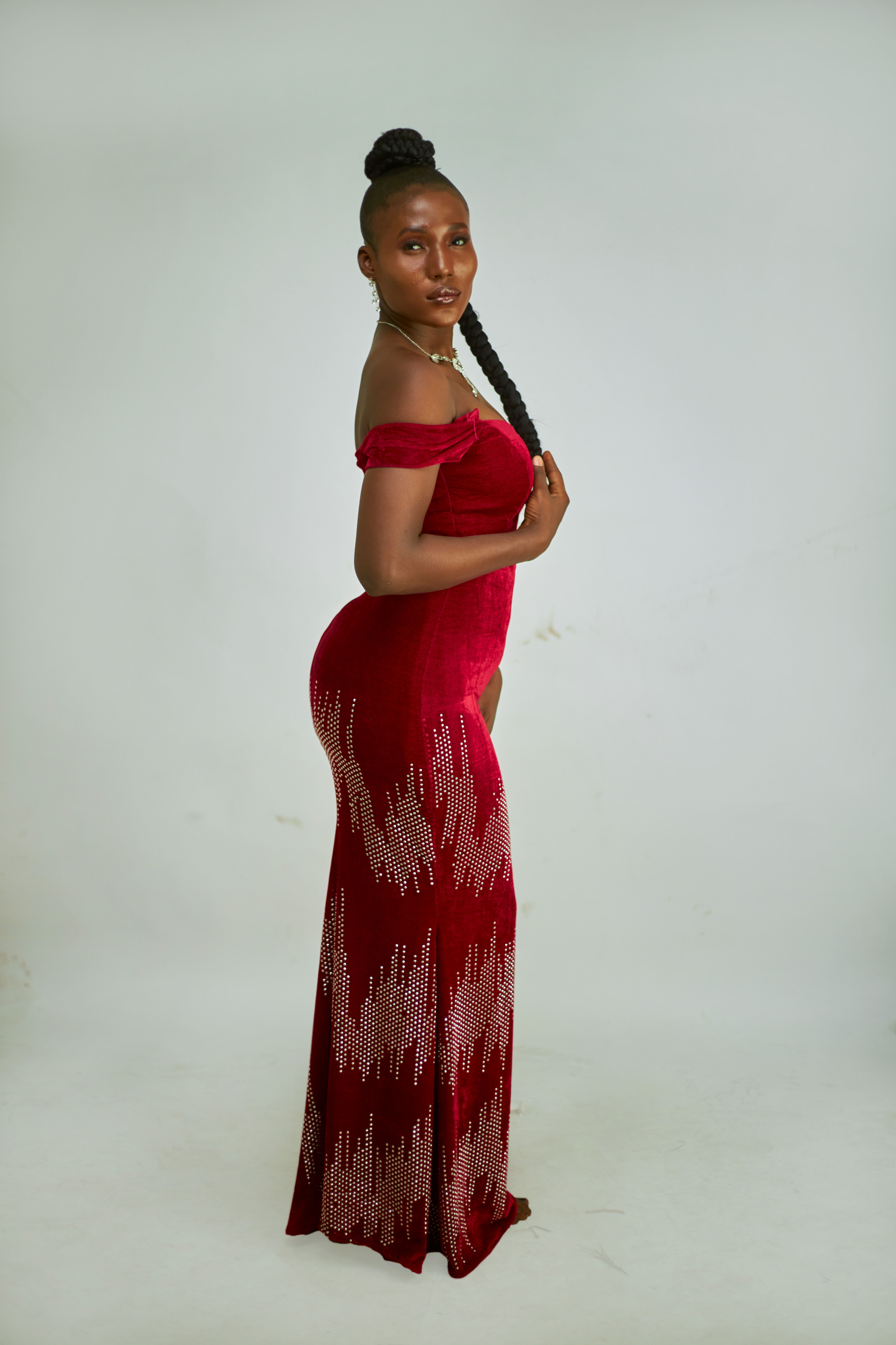 Elegant portrait of a woman in a stylish red off-shoulder dress with braided hairstyle.