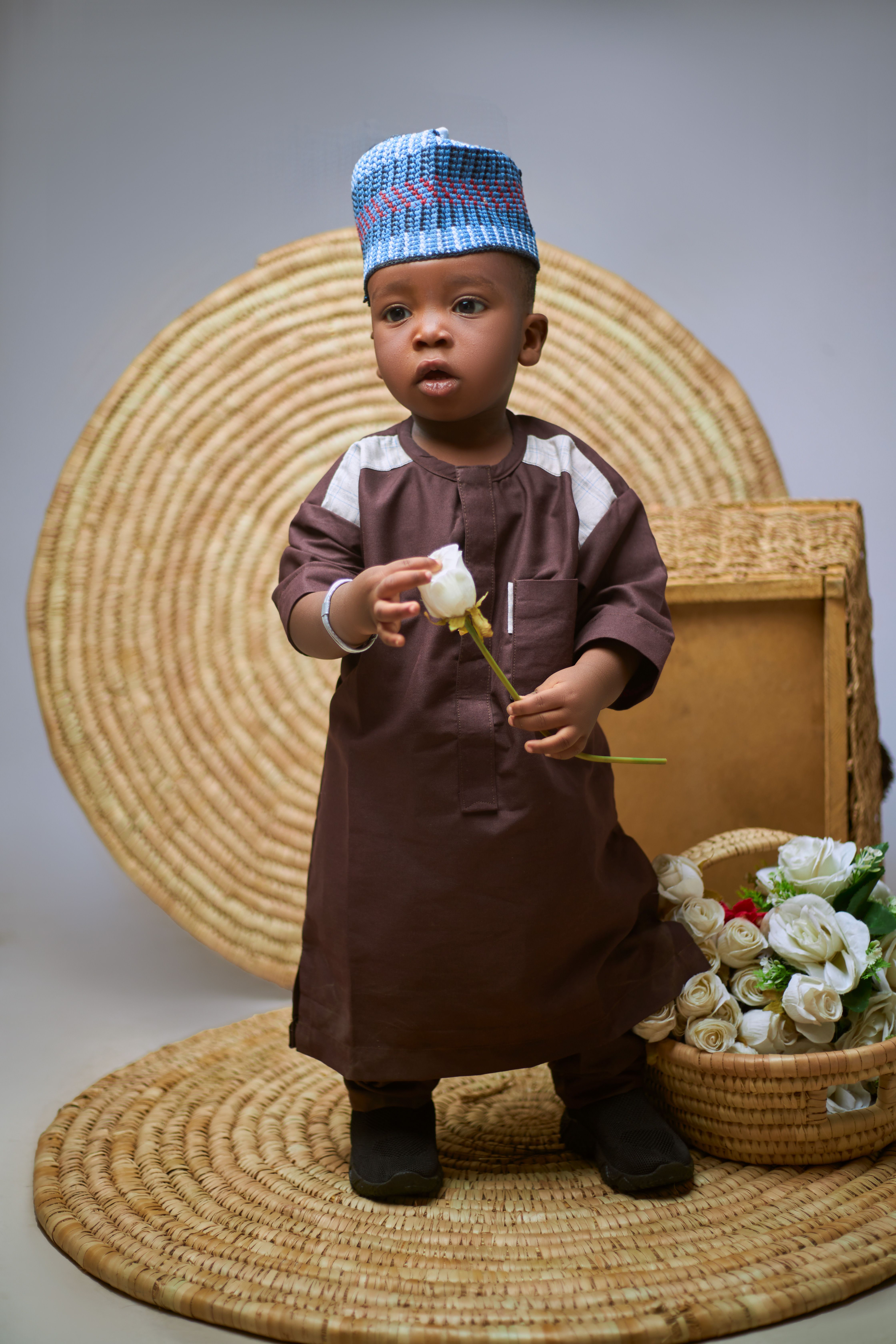 Cute child in African wear holding a flower, adding charm to traditional cultural style.