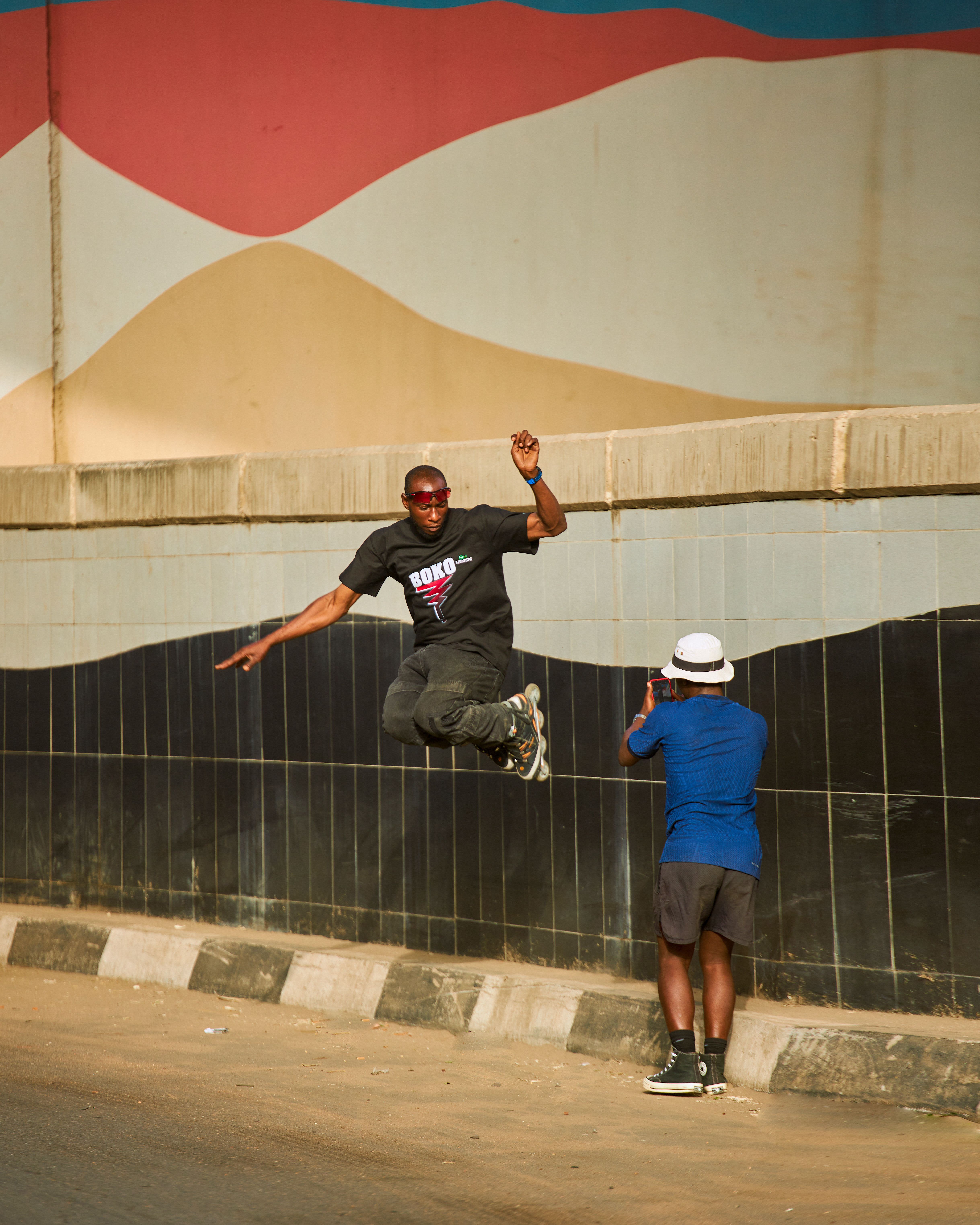 Candid moment of a person jumping in front of a colorful urban wall.
