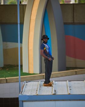 A man in casual attire stands confidently on a rooftop, urban colorful backdrop.