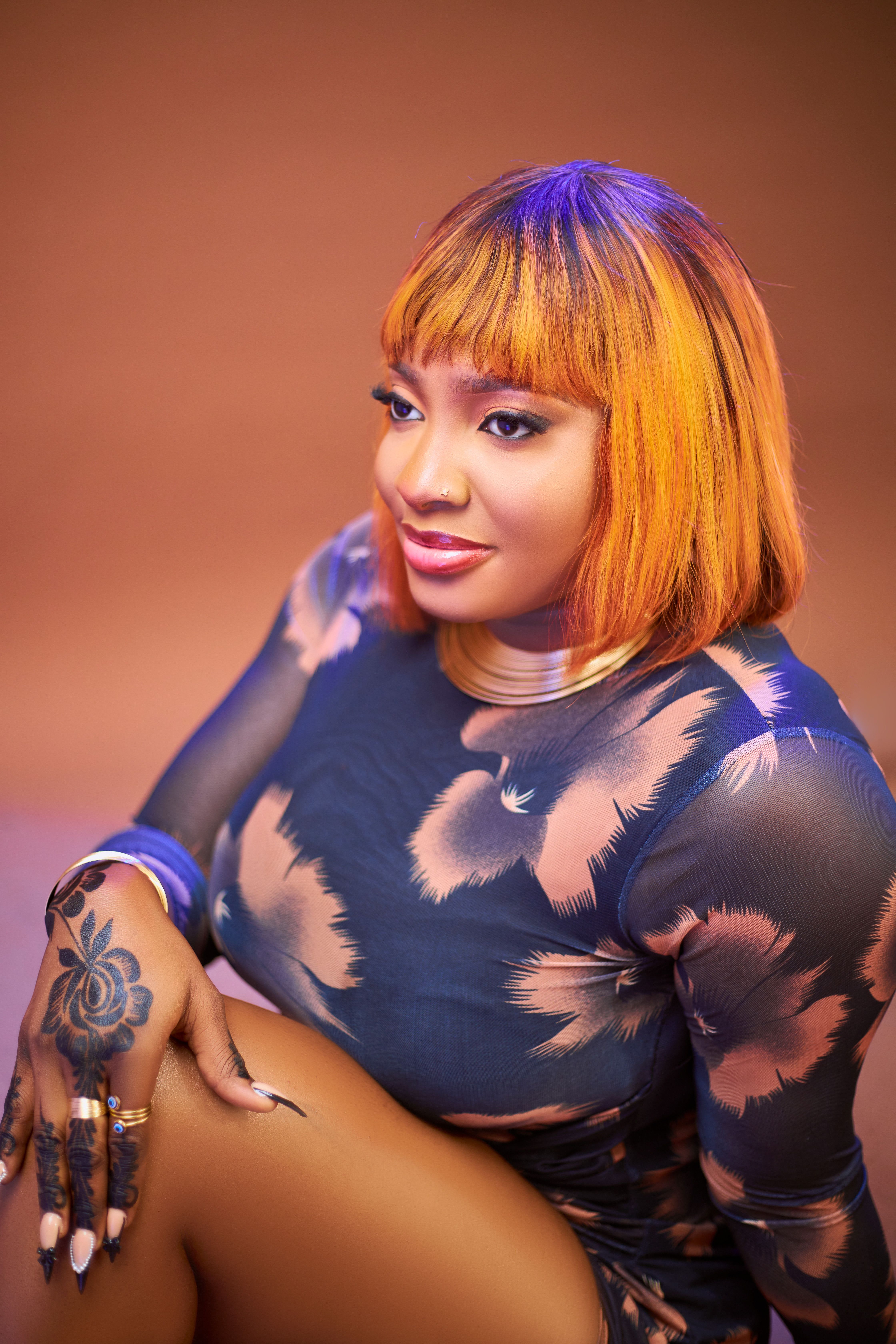 A vibrant portrait of a woman in a stylish floral dress with bold tattoos.