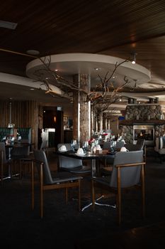 Dimly lit modern restaurant interior with rustic decor and a cozy fireplace.