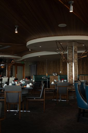 Dim dining room with timber ceilings and banquette seating, photo by Anastasia Nagibina on Pexels
