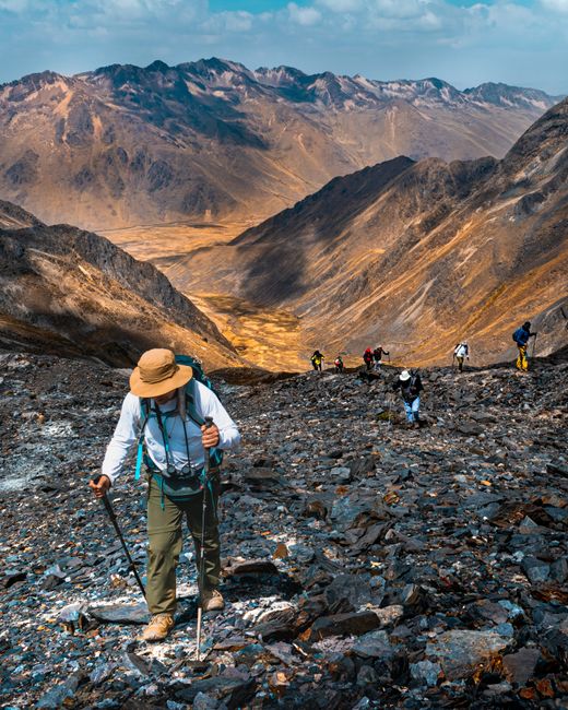 Hikers trekking the Andes mountains in Cuzco, Peru, under a clear sky.