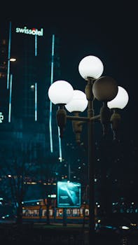 Illuminated street lamp with Swissotel in the background at night.
