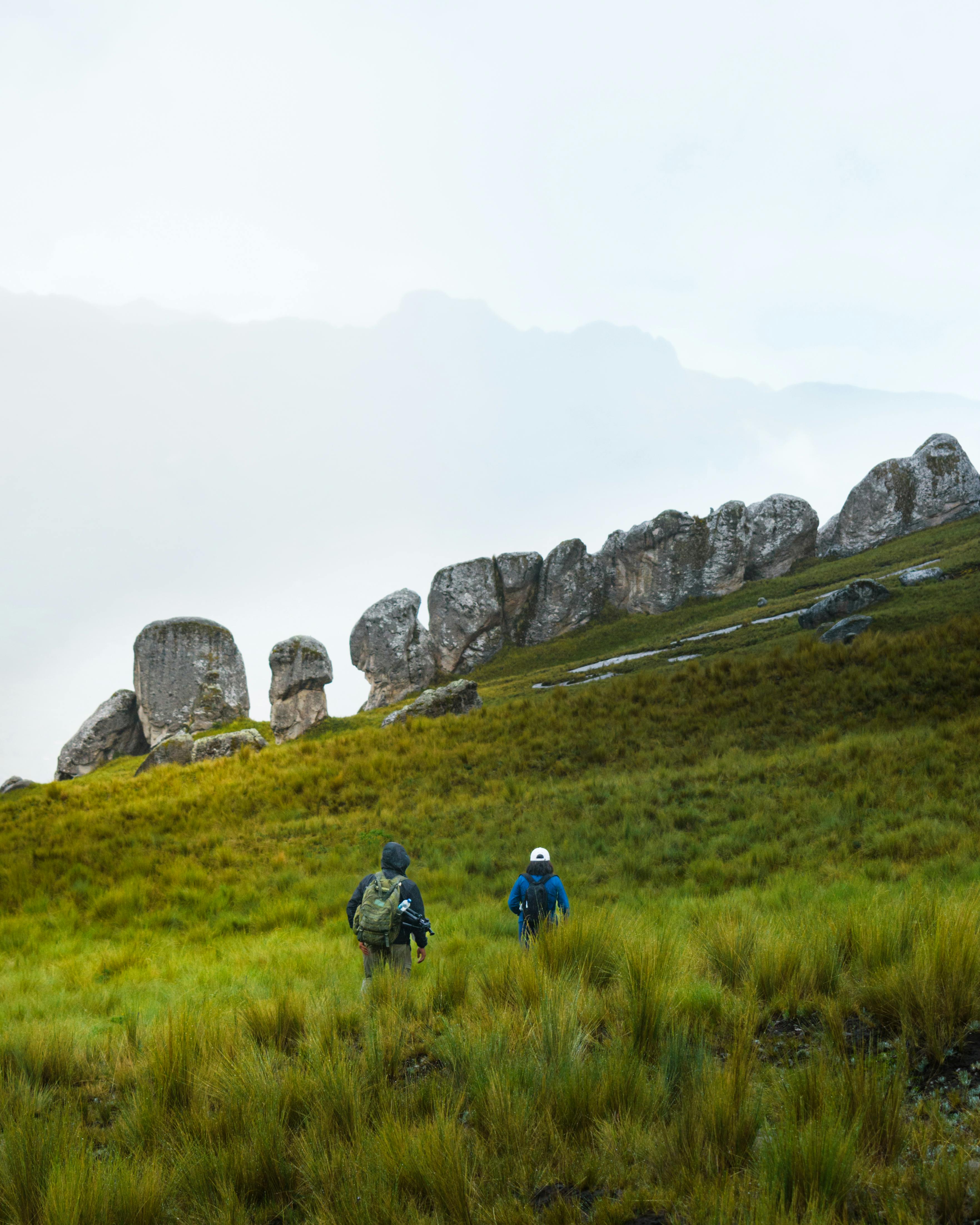 Hikers exploring the lush, rugged terrain of Ancahuasi, Peru with dramatic rock formations.