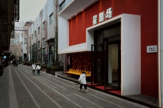 Exterior of a modern theater with a striking red facade in a vibrant urban environment.
