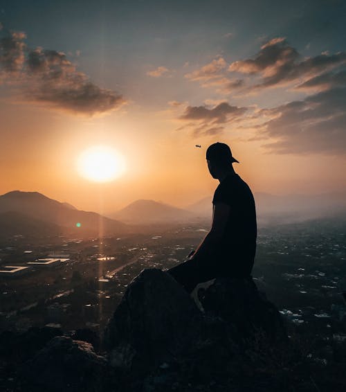 Man Sitting on Rock During Golden Hour