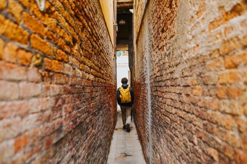 Figure walking a narrow brick passage — photo by Helena Jankovičová Kováčová on Pexels