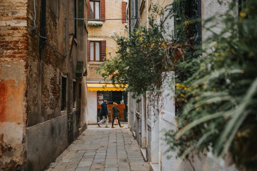 Atmospheric narrow alley with rustic buildings and walking people in a historic European town.