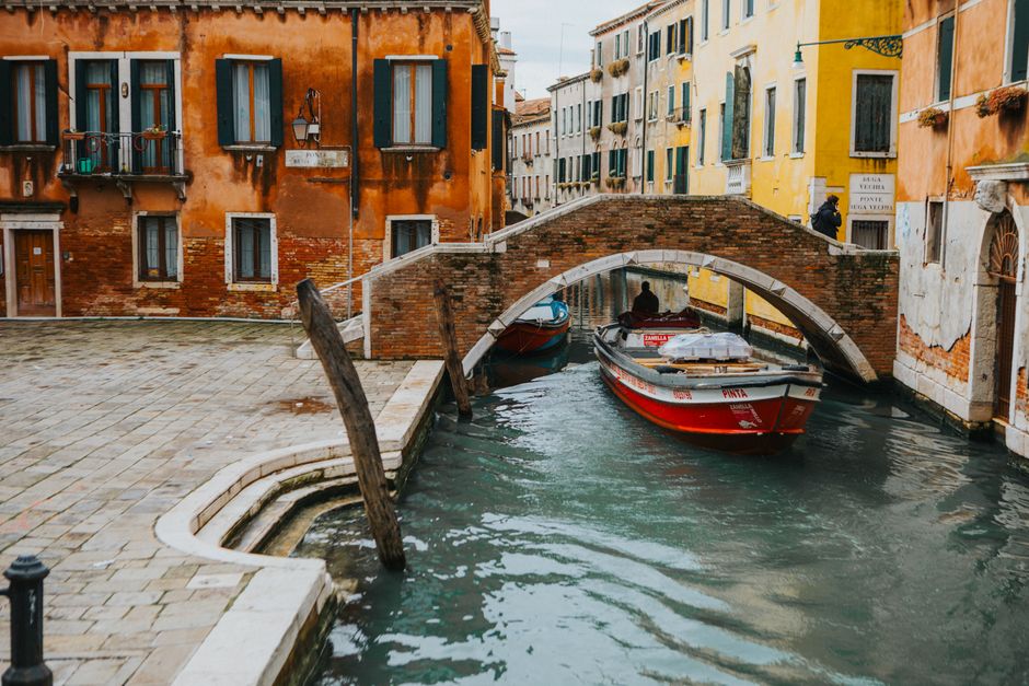 Picturesque canal scene in Venice, showcasing a historic bridge and colorful buildings.