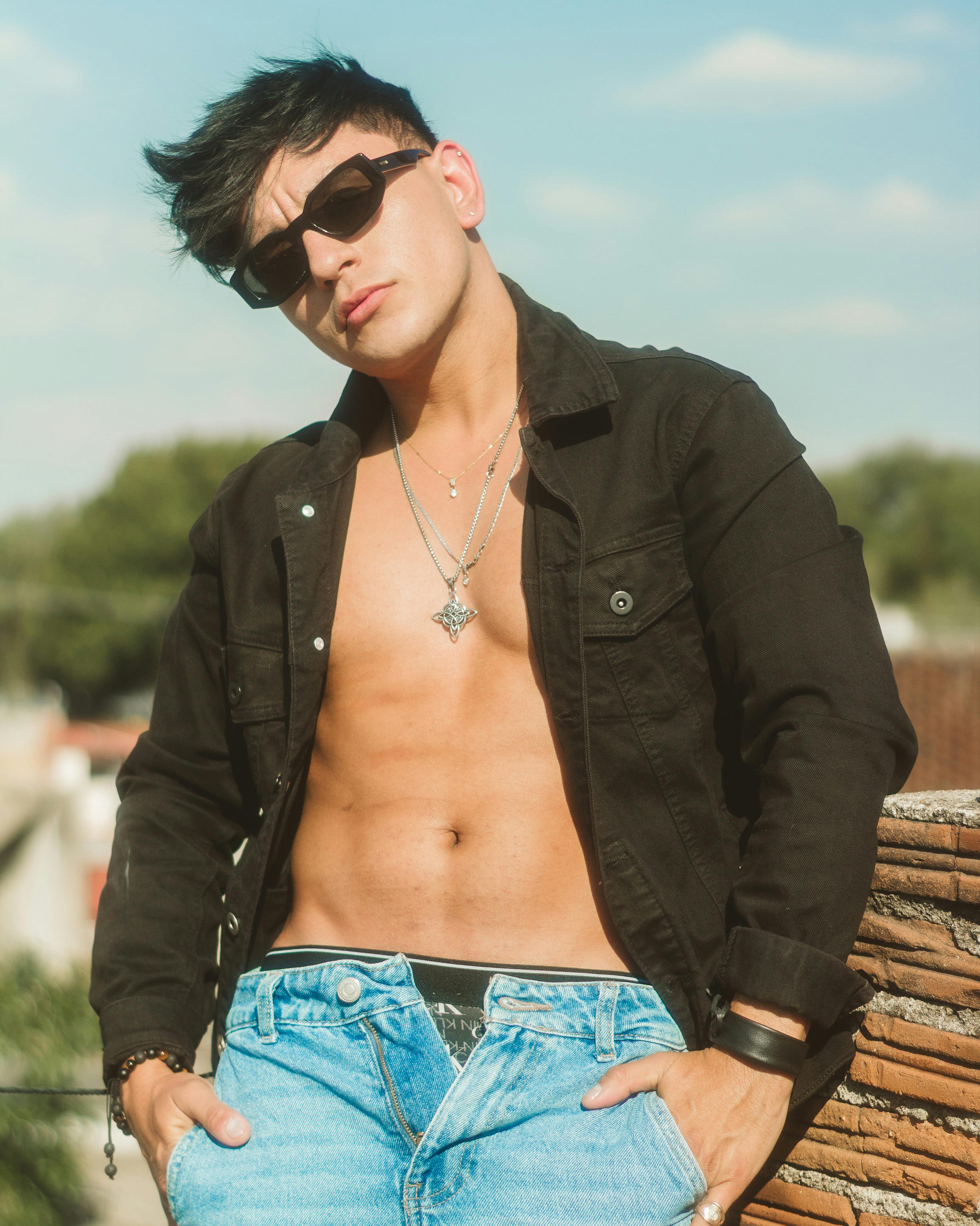 Confident young man in sunglasses posing outdoors with casual fashion style.