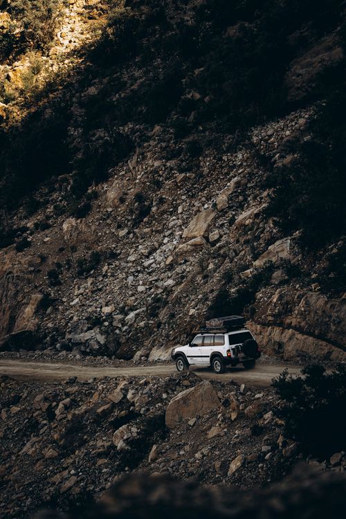 Free SUV navigating rocky mountain trail in Oman, showcasing offroad travel. Stock Photo