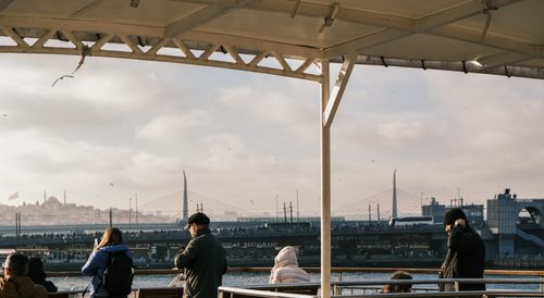 Free Passengers on ferry with Istanbul skyline and bridge in background under cloudy sky. Stock Photo