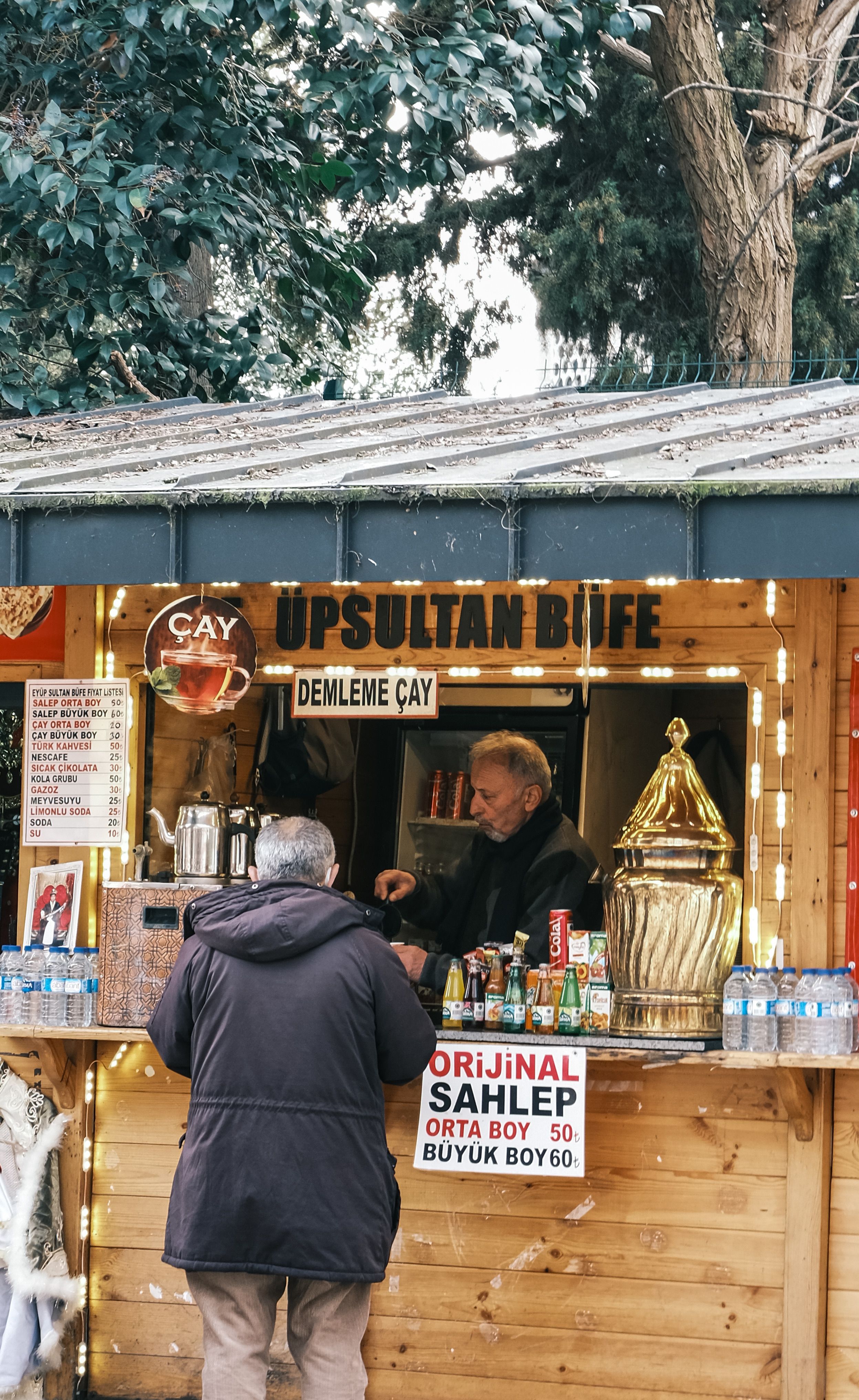 Street vendor serving traditional Turkish tea and sahlep at an outdoor kiosk.