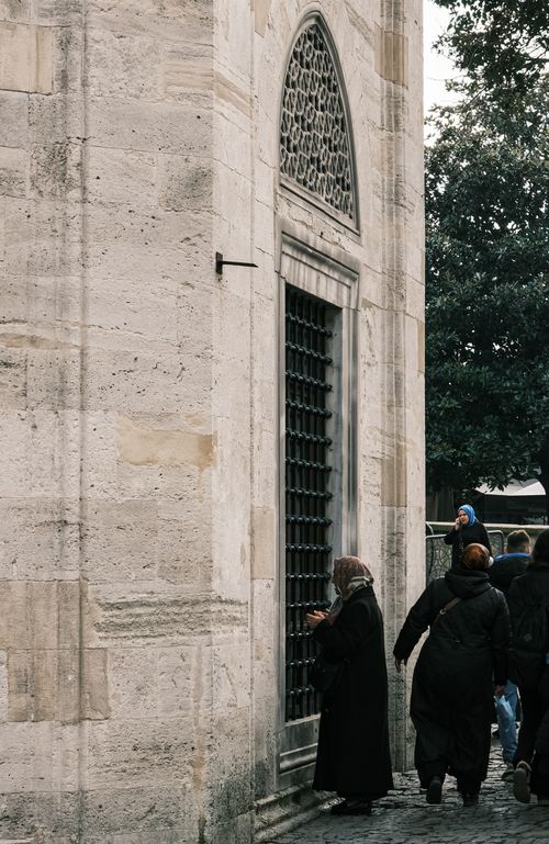Free A group of adults near a historic stone building facade with an ornate iron door. Stock Photo