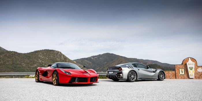 Two luxury sports cars parked with a scenic mountain backdrop. Perfect for automotive enthusiasts.