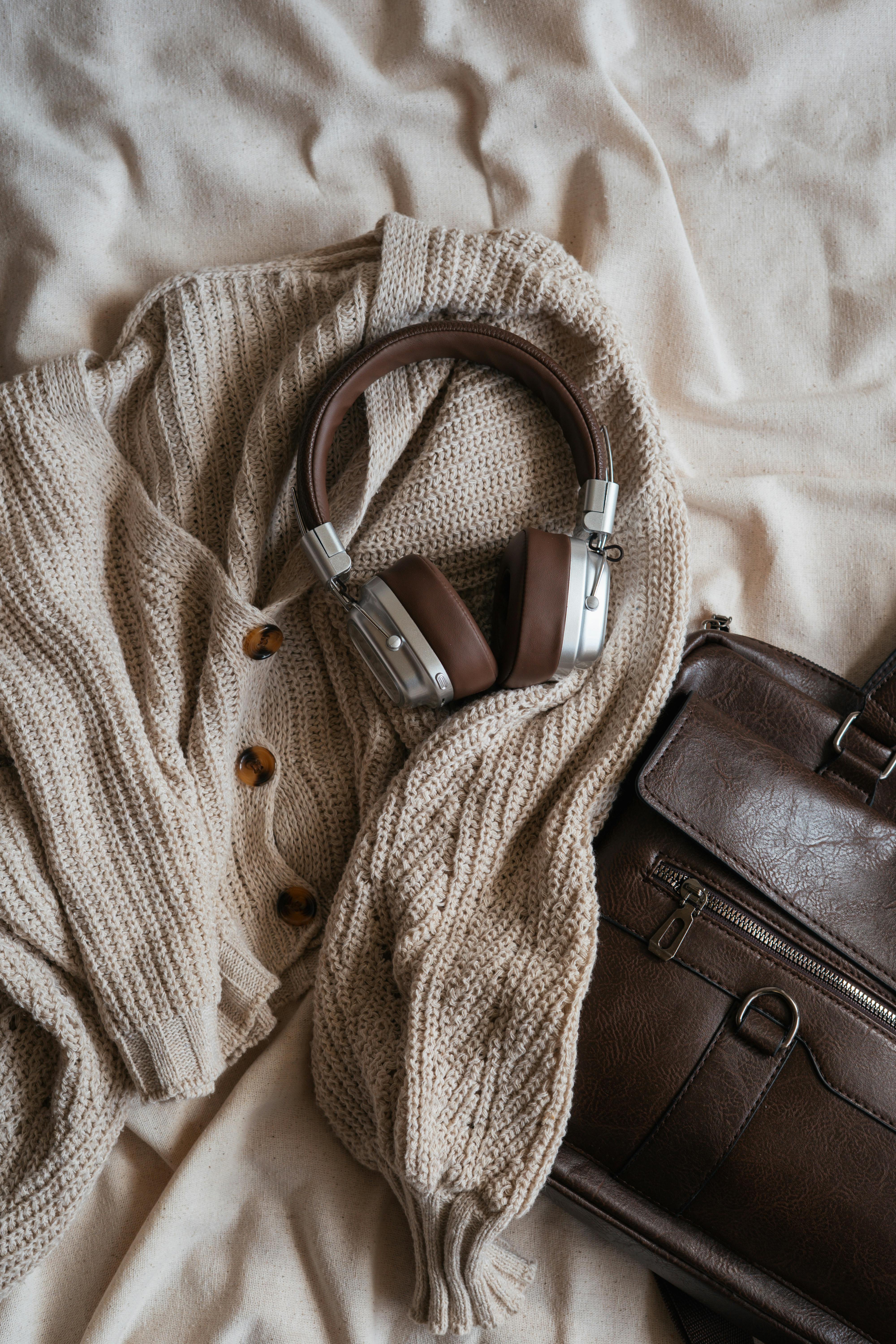 Comfortable knitted sweater with headphones and leather bag in warm tones.