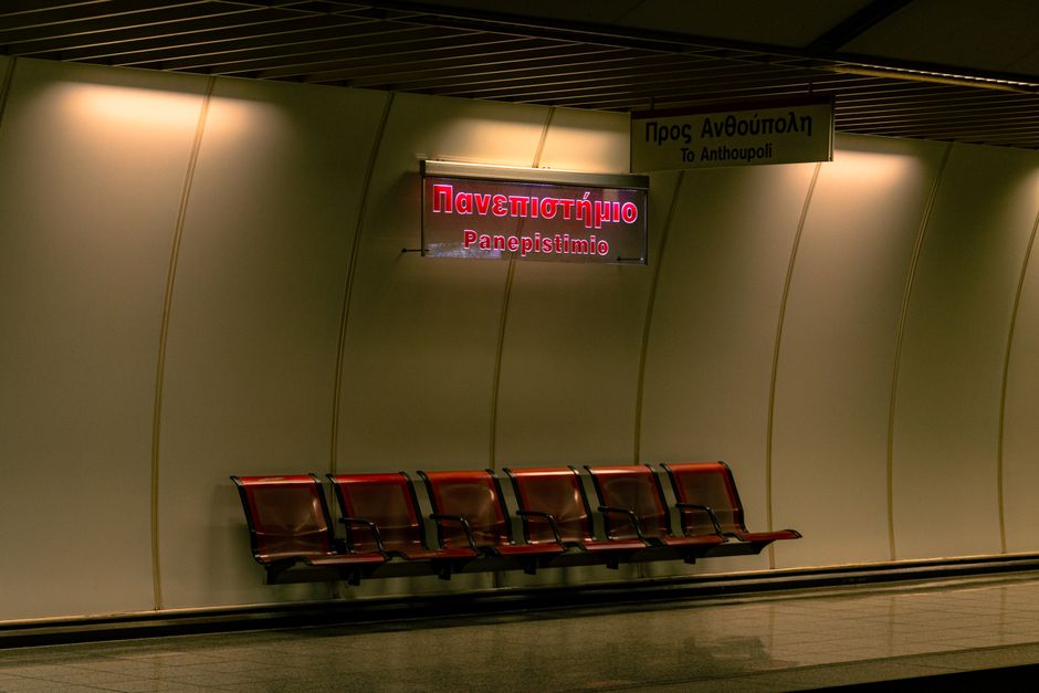 Empty Athens metro station with benches and signage at night, creating a quiet urban ambiance.