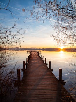 Beautiful sunrise at Wörthsee with a wooden pier stretching into the calm lake.