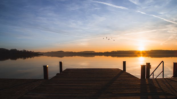 Sunrise over a tranquil Wörthsee lake with a wooden pier, capturing serene beauty and vibrant colors.
