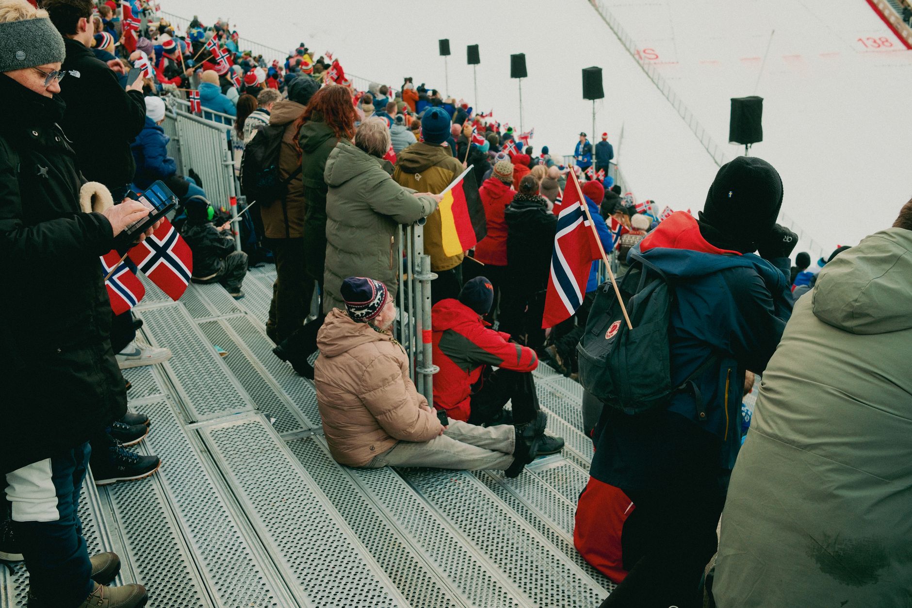 Spectators with Norwegian flags at a winter sports event, capturing the festive spirit.