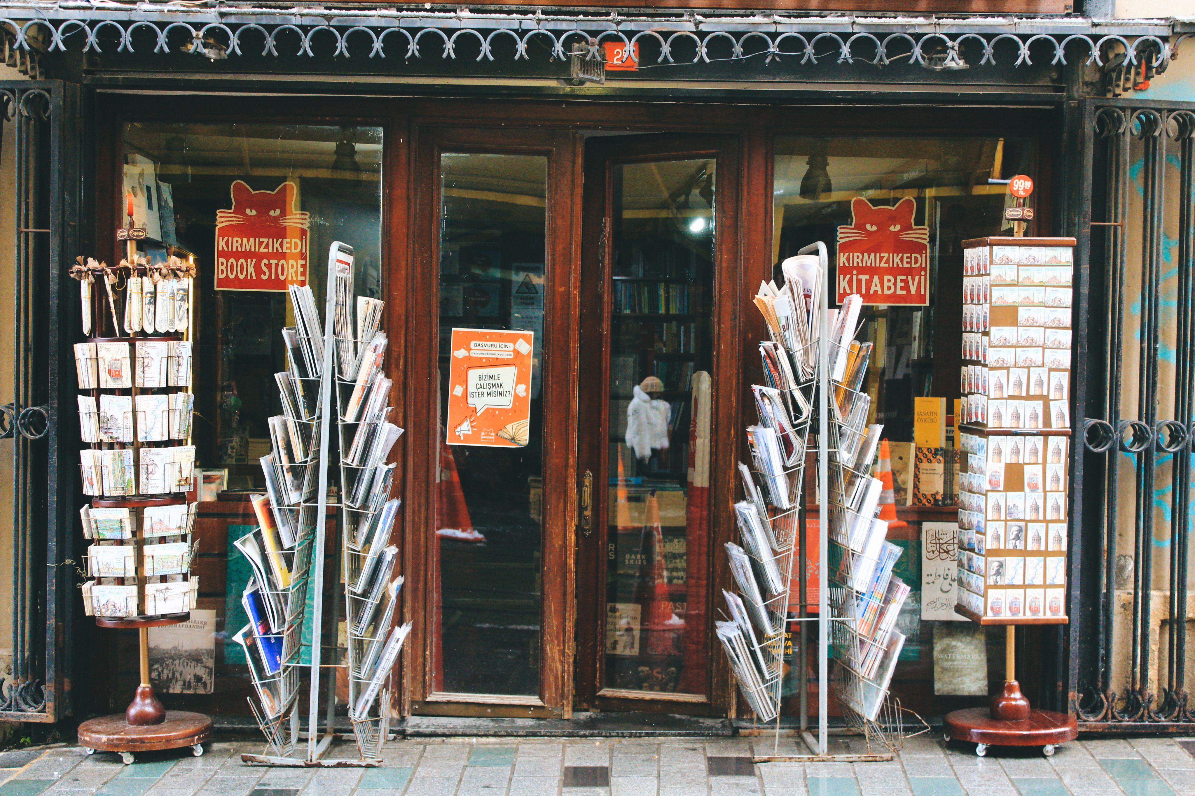 Exterior view of Kirmizikedi bookstore with colorful magazine racks outside.