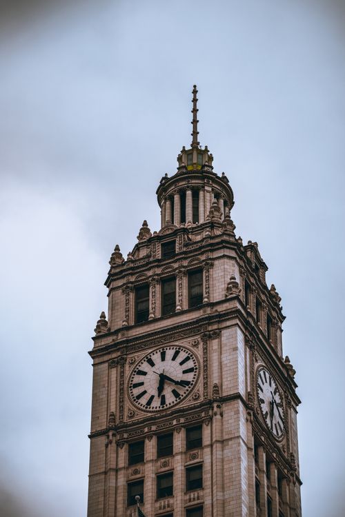 Free Wrigley Building's clock tower against a cloudy sky in Chicago, IL. Stock Photo