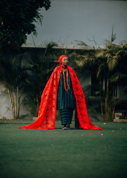 Free A woman stands outdoors in striking red traditional attire, exuding elegance and cultural richness. Stock Photo
