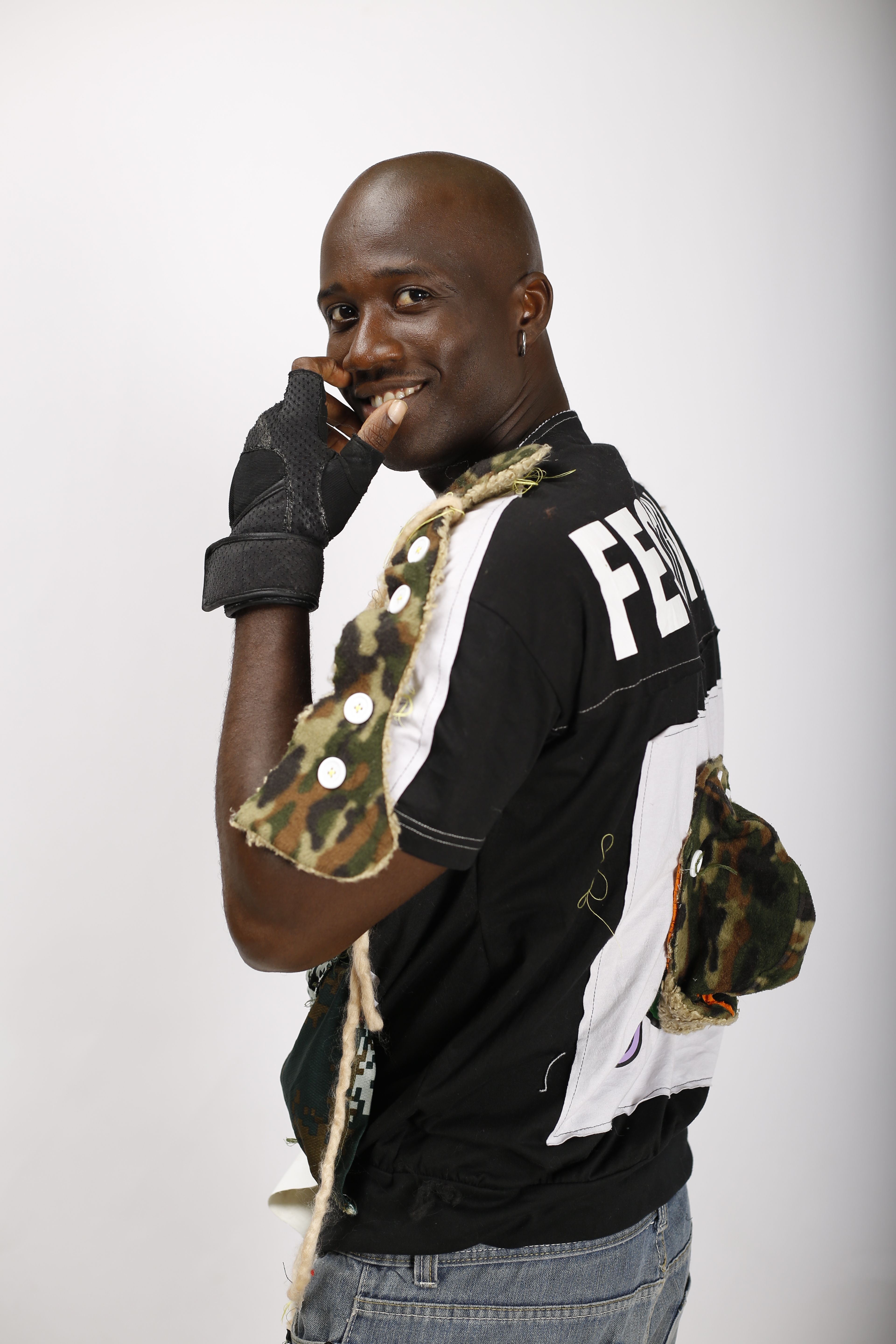 Man wearing a stylish outfit and gloves poses confidently, showcasing unique fashion.