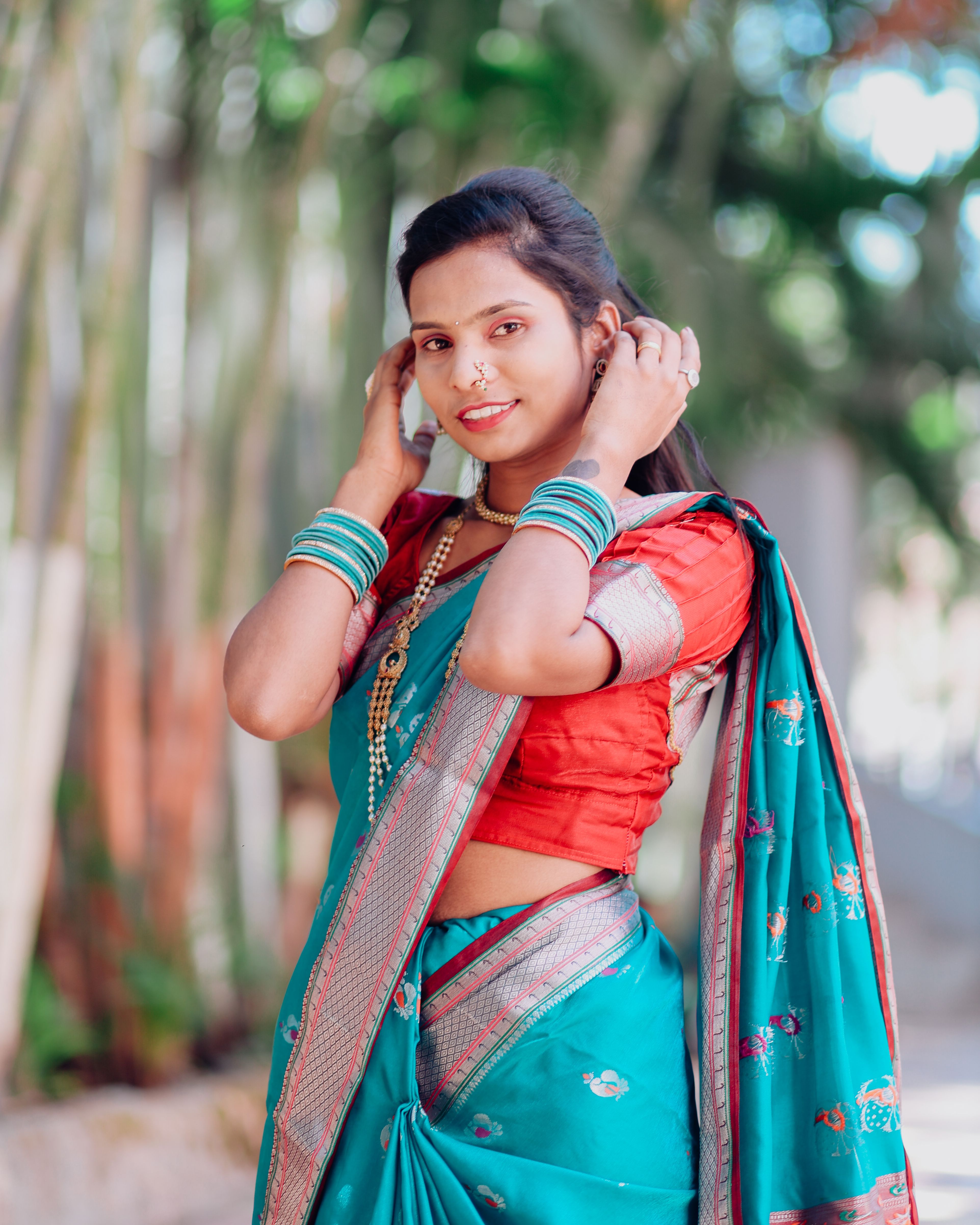 Elegant woman in a blue traditional sari posing outdoors, showcasing cultural attire.