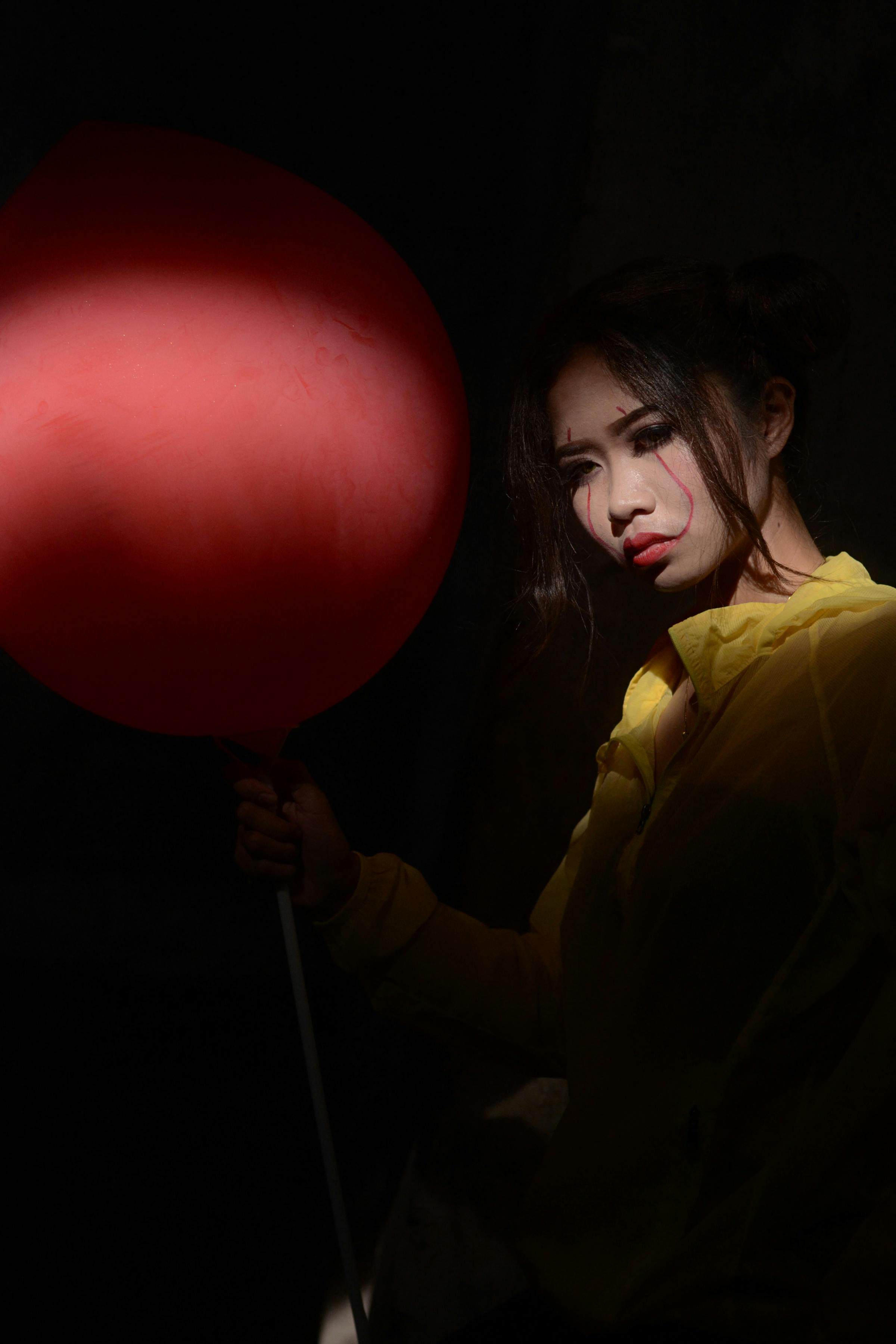 woman wearing yellow top holding red balloon