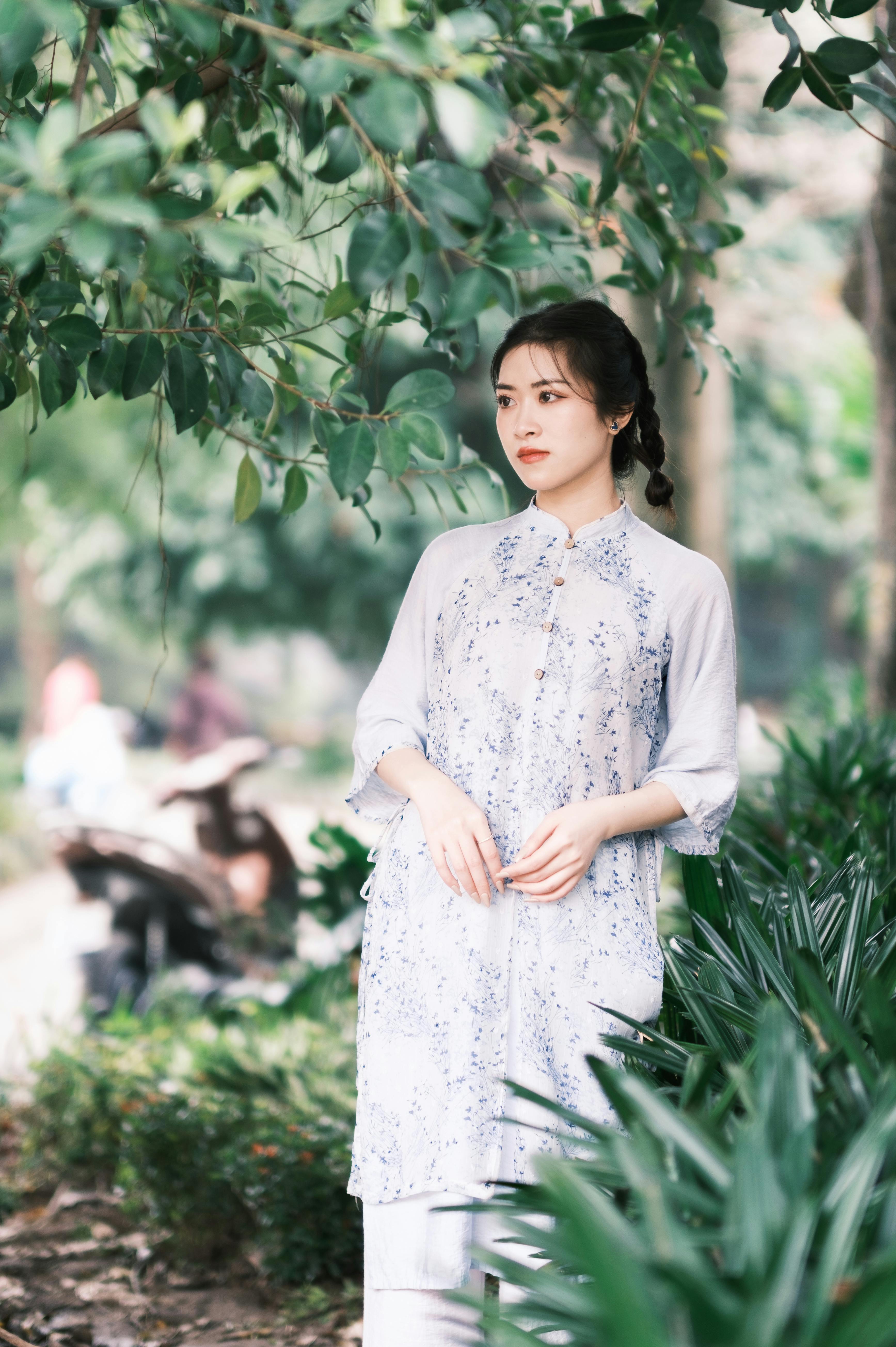 A serene portrait of a young woman in a light blue dress surrounded by lush greenery.