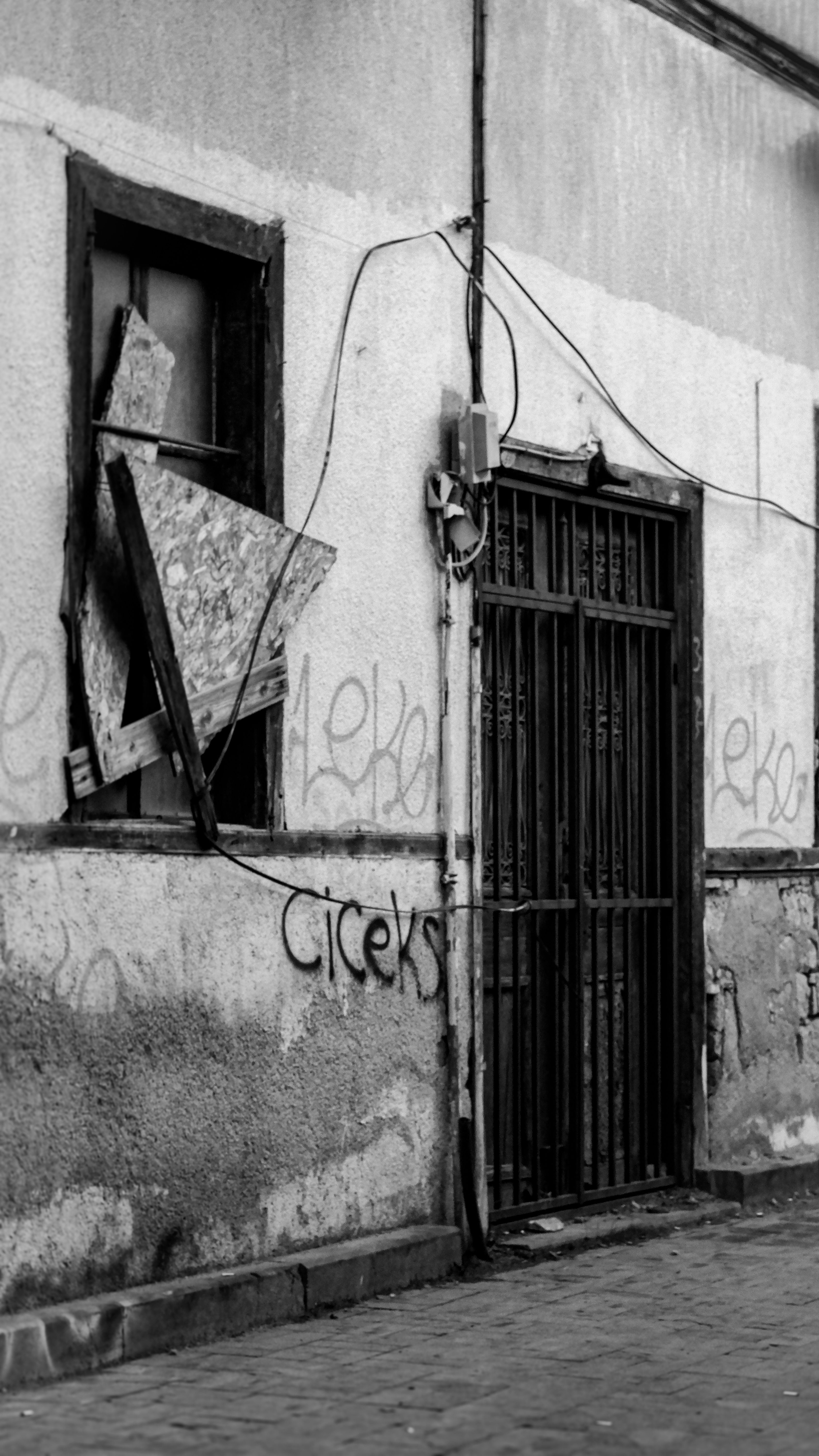 Black and white photo of an abandoned building with graffiti and broken window.