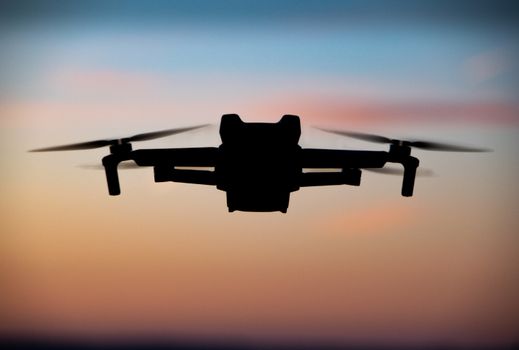 Silhouette of a drone flying across a colorful sunset sky in Bad Mergentheim, Germany.