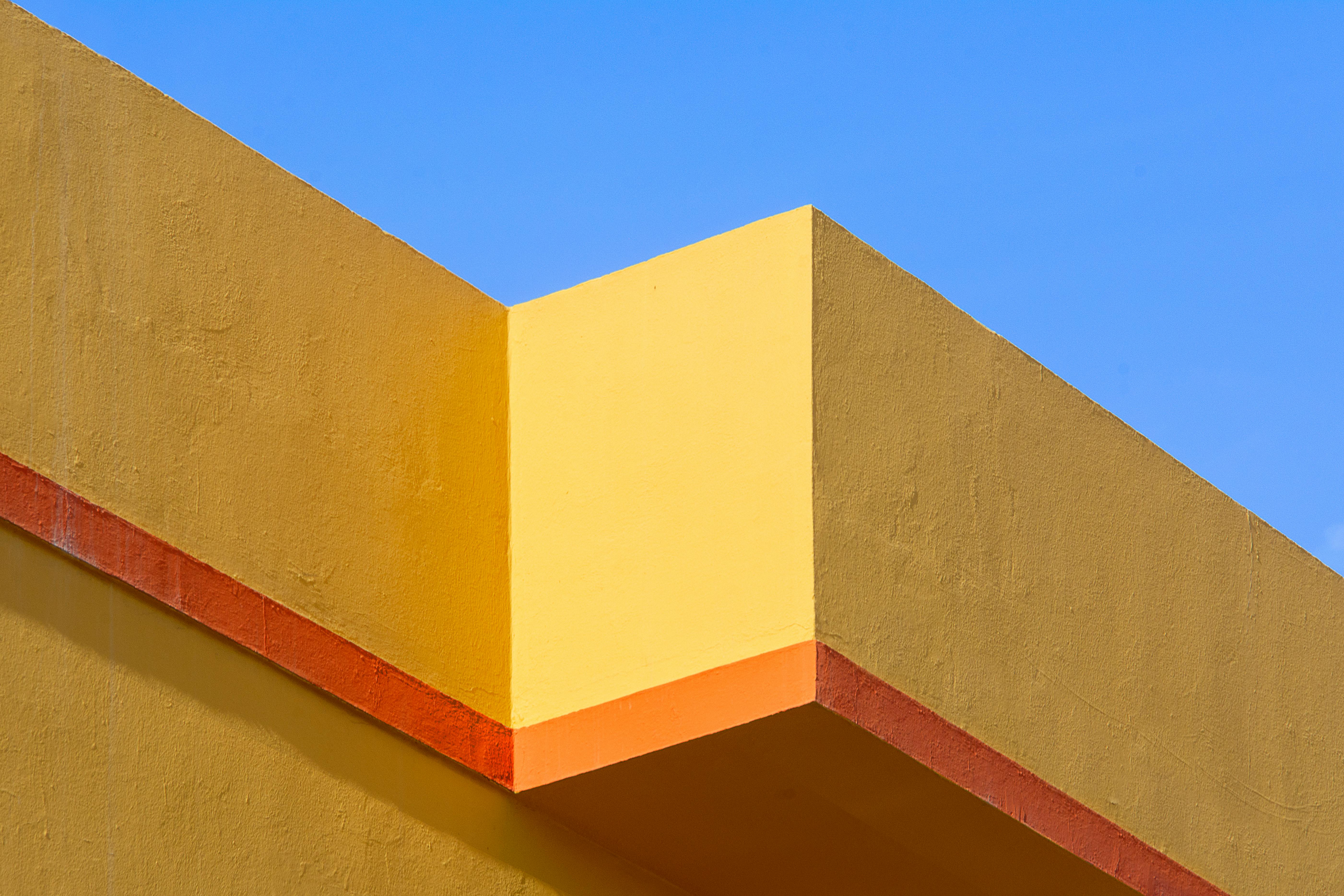 gratis Levendige architectonische details met gele en oranje tinten die contrasteren met de helderblauwe lucht. Stockfoto