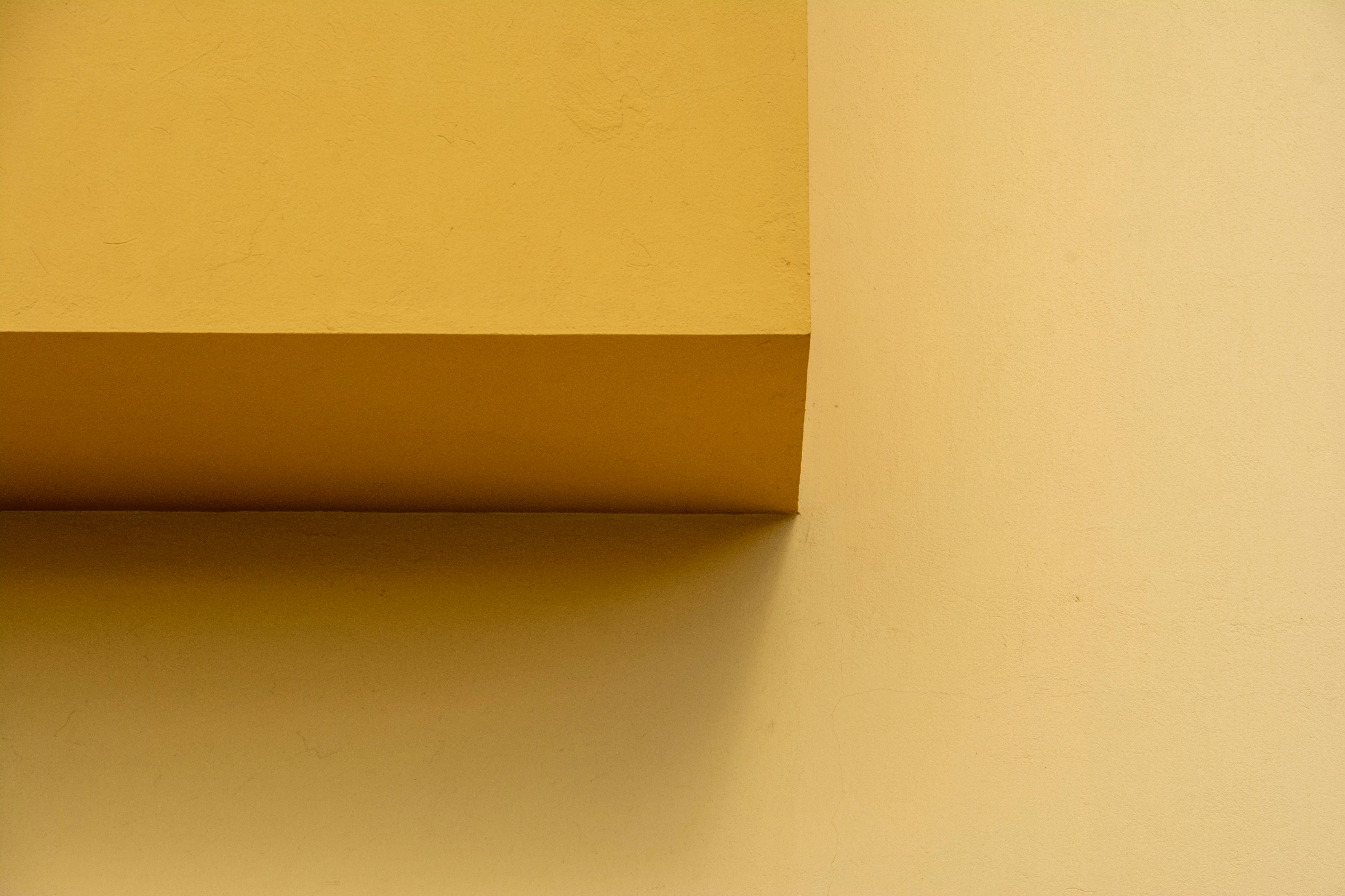 De franc Una visió minimalista i geomètrica d'una paret groga amb ombres agudes que creen interès arquitectònic. Foto d'estoc