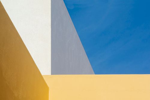 Free Modern minimalist architecture with bold yellow, white, and blue tones under a clear sky. Stock Photo