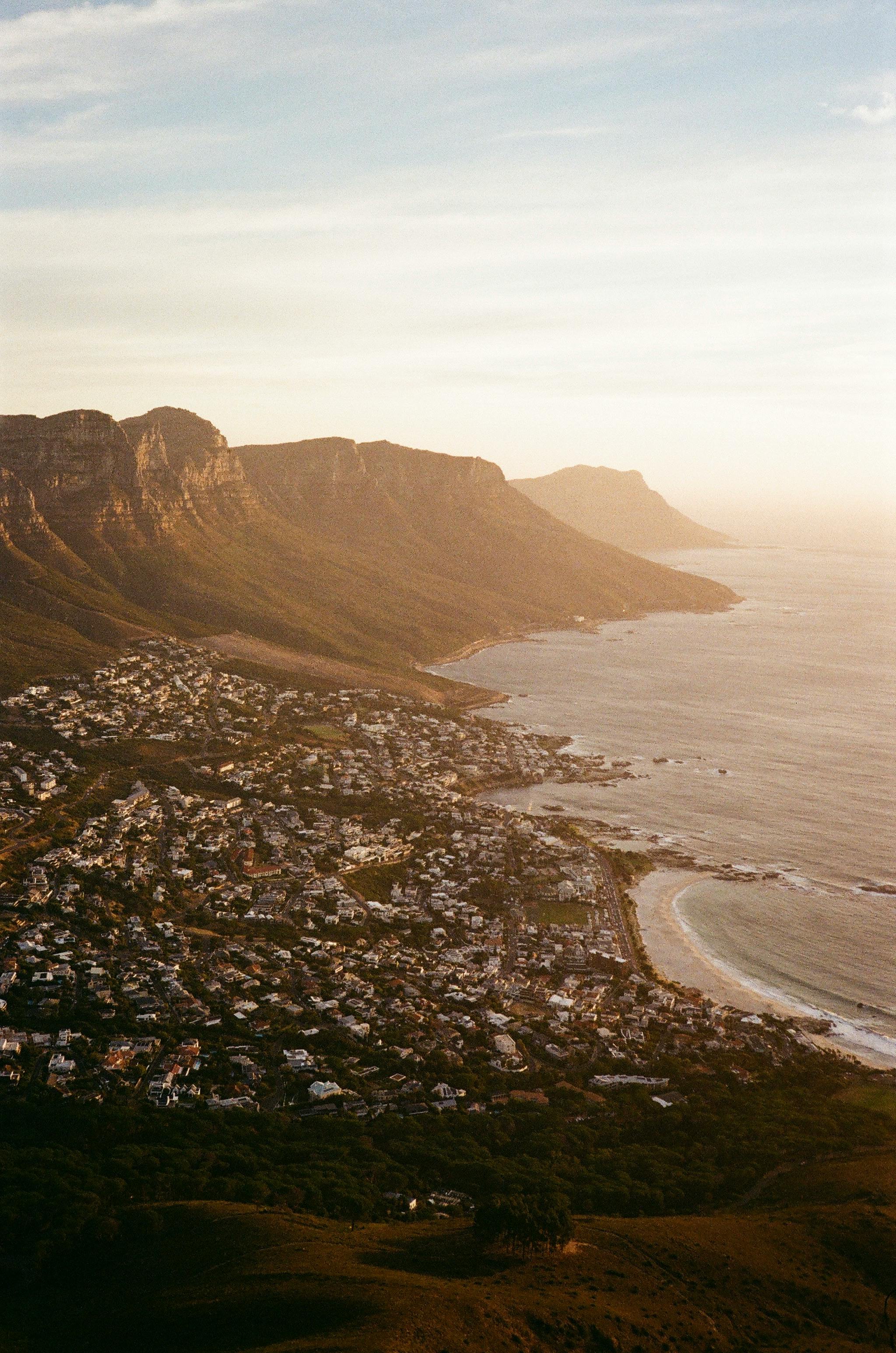 A breathtaking aerial shot of Cape Town's coastline with mountains and ocean at sunset.