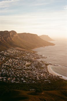A breathtaking aerial shot of Cape Town's coastline with mountains and ocean at sunset.