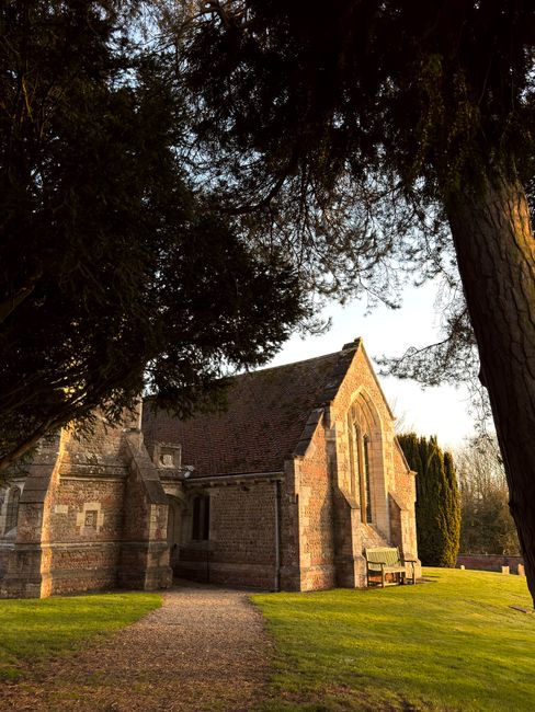 Scenic view of historic church in Aldwark, England, surrounded by greenery at sunset.