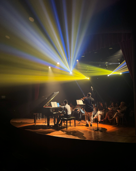 Piano and violin duet on stage with vibrant lighting effects, captivating the audience.