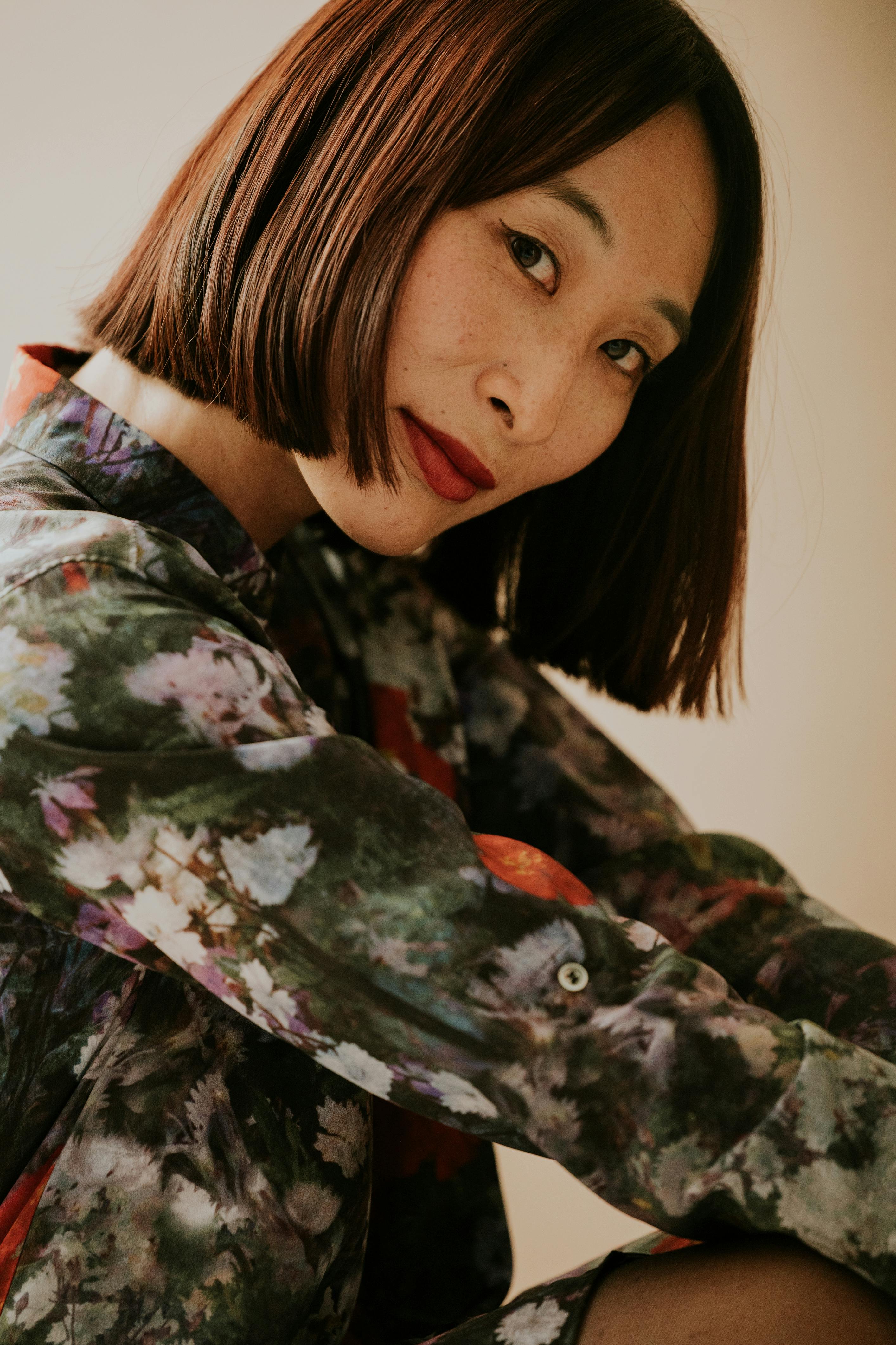 Artistic portrait of a woman in floral attire with a warm tone and soft focus, shot indoors.