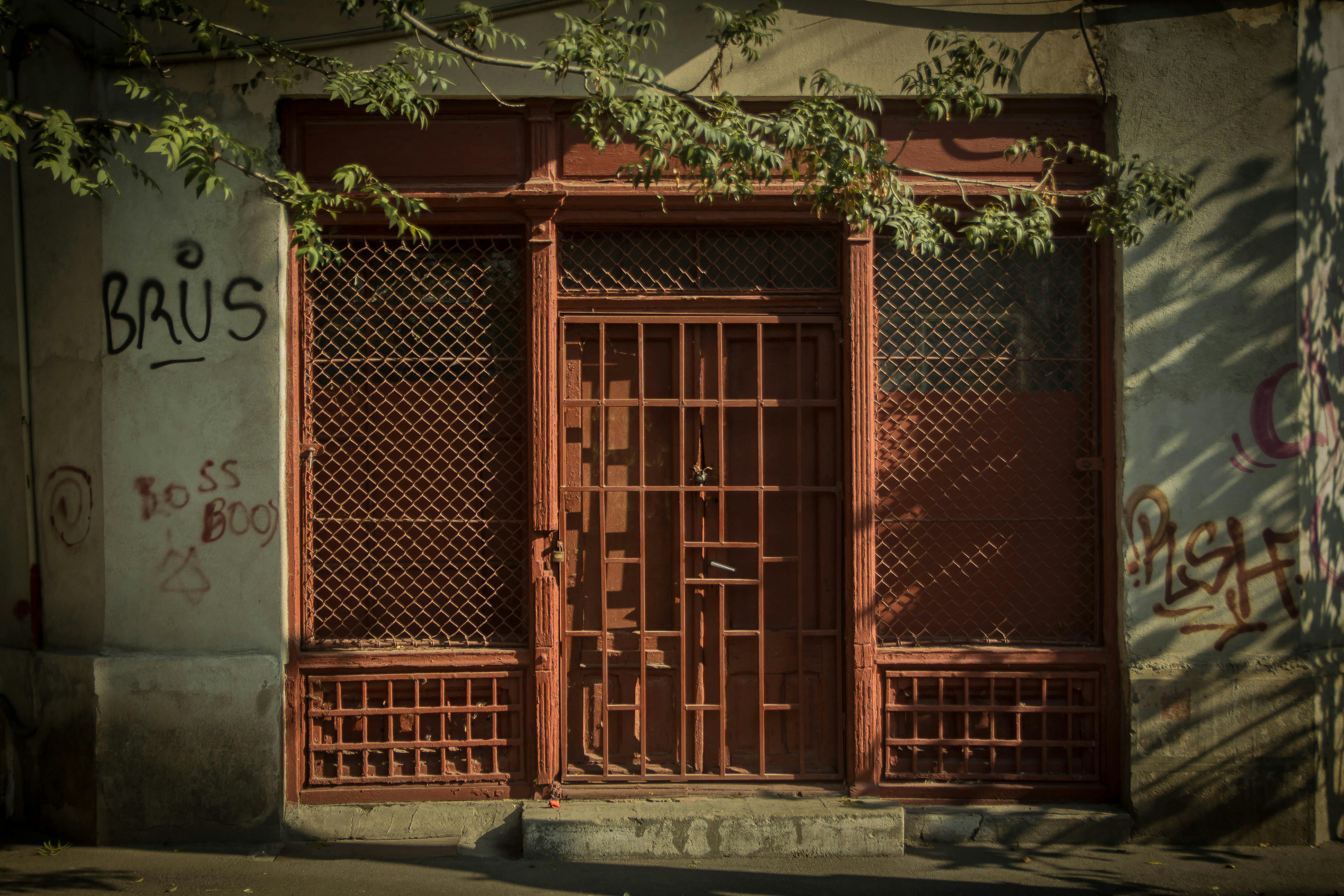 Kostnadsfria En rustik metalldörr med graffiti i ett urbant område, som visar upp vintagecharm och gatukonstkultur. Stock foto