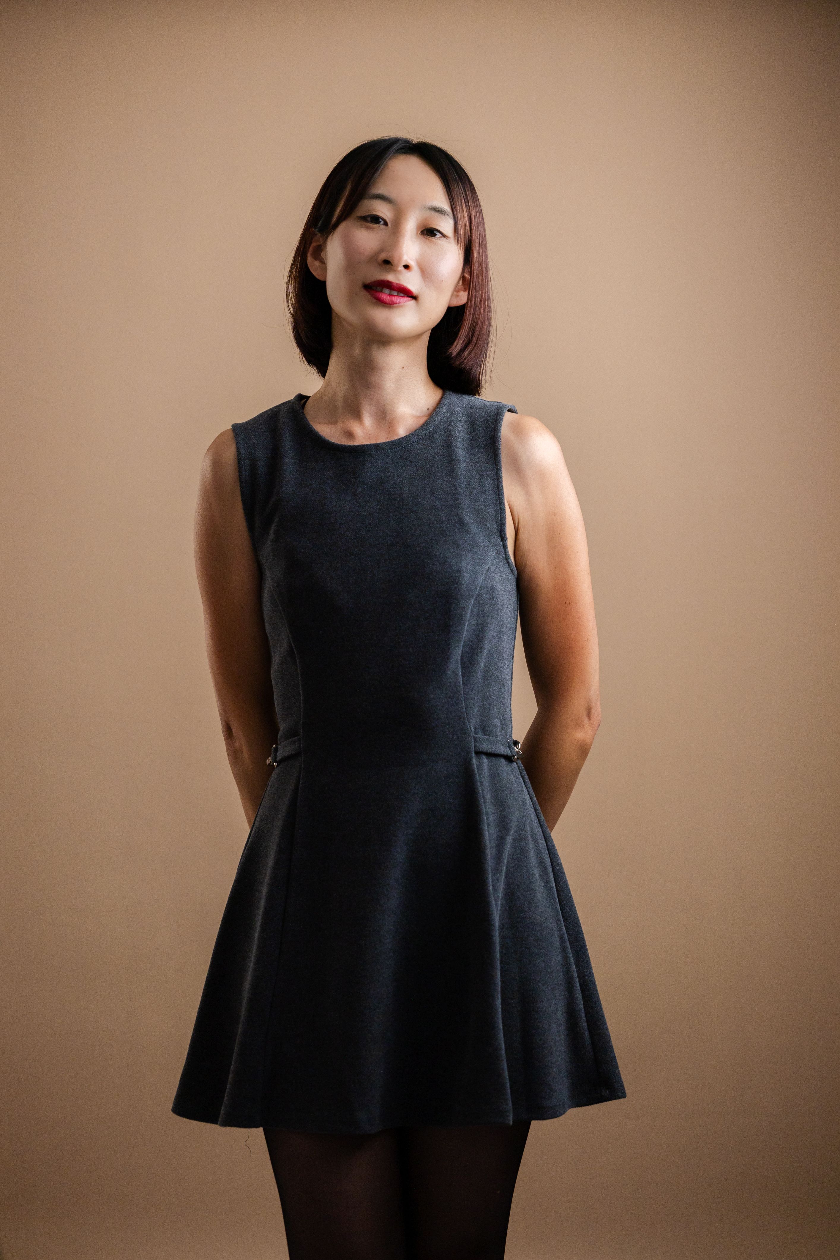 Stylish portrait of an adult woman wearing a dark dress in a studio setting.